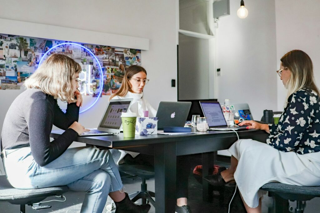 Make Black Friday Work for Your B2B Business 3 3. Three women seated at a table, each using a laptop, representing a collaborative work environment.